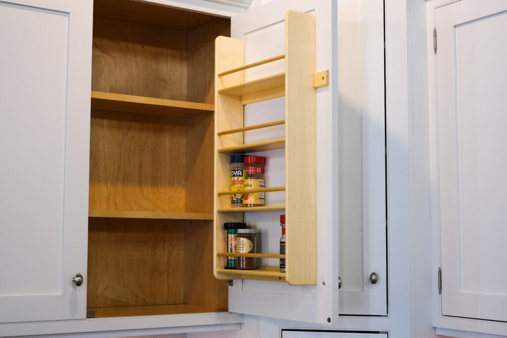 A spice rack insert attached to the back of a wall cabinet door.